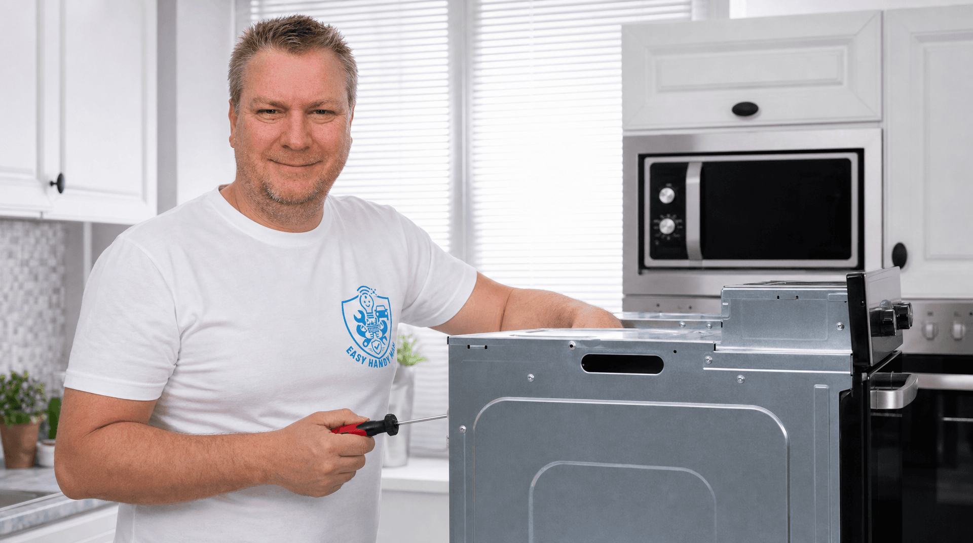 Handyman installing a built-in oven with a screwdriver in a modern kitchen